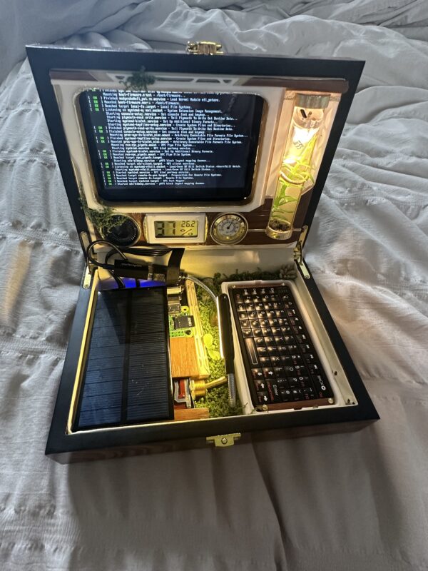 Open steampunk-inspired computer case with a terminal screen, compact keyboard, exposed circuitry, gauges, and warm yellow lighting.